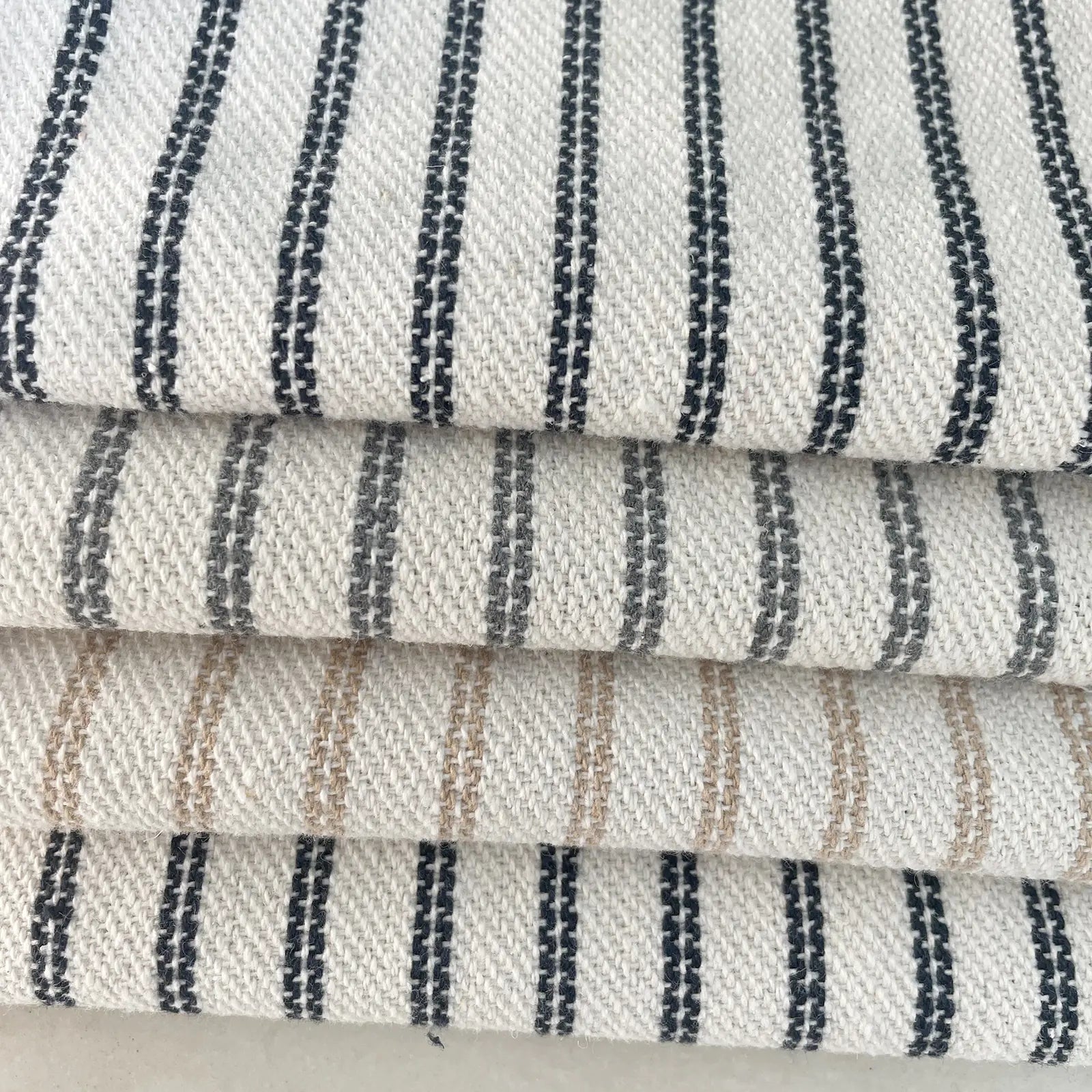 Close-up of striped fabric with black, grey, blue and beige lines on a neutral background