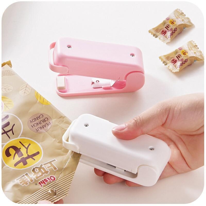 Pink and white Mini heat bag sealer devices with small packages on a white background