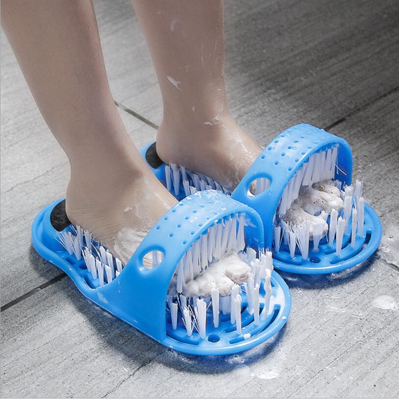 Two blue foot massager bath slippers with soft bristle brushes on feet on a tiled floor.