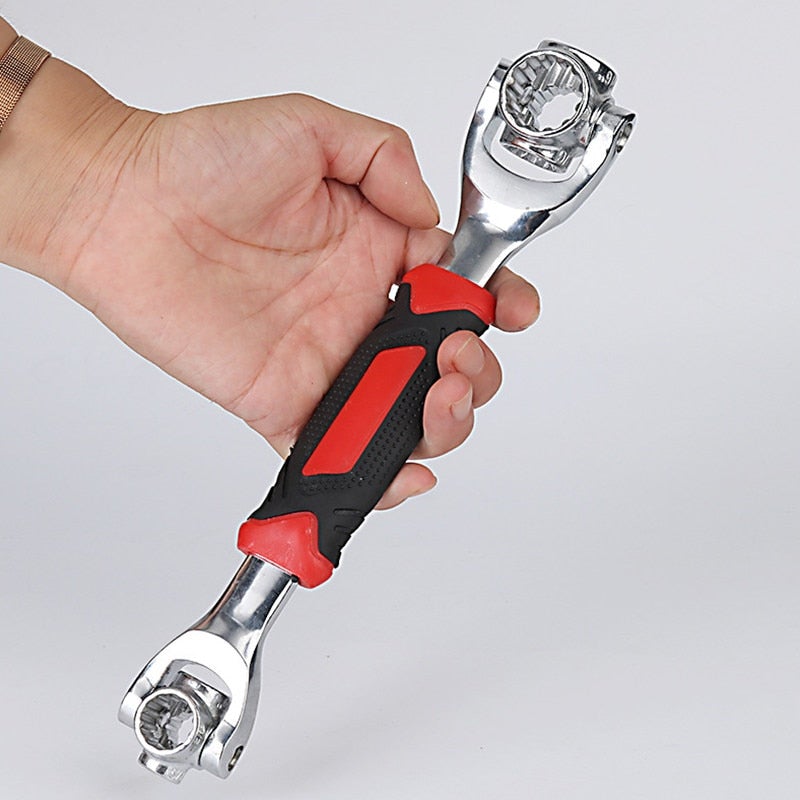 Hand holding a wrench with red and black handle on a light grey background