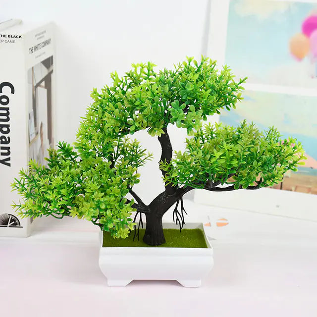 Artificial bonsai tree in a white pot on a table with a blurred background