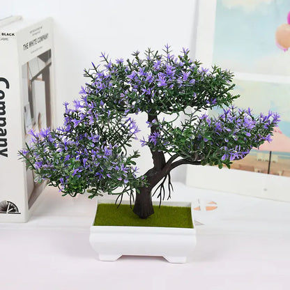 Artificial bonsai tree with purple flowers in a white pot on a light surface.