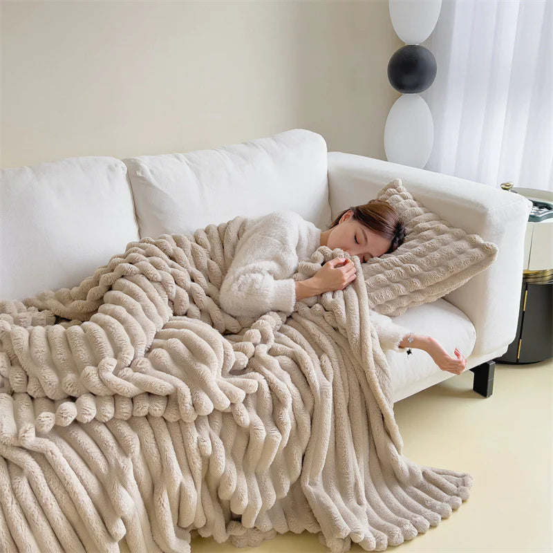 Beige cosy ribbed fleece throw blanket in neutral colour draped over couch, soft textured warm blanket for home comfort and relaxation.