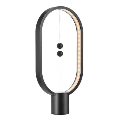 Black LED magnetic table lamp with suspended magnetic sphere switch creating ambient warm lighting on a white background