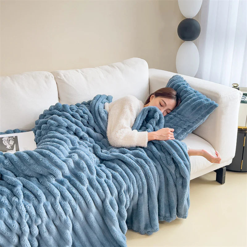 Blue cosy ribbed fleece throw blanket in neutral colour draped over couch, soft textured warm blanket for home comfort and relaxation.