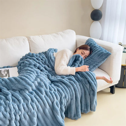 Blue cosy ribbed fleece throw blanket in neutral colour draped over couch, soft textured warm blanket for home comfort and relaxation.
