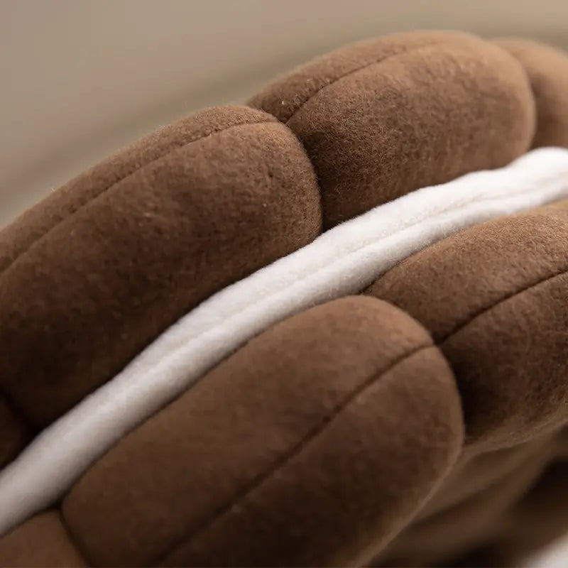 Close up of biscuit shaped plush cushion chocolate coffee plush cushions with a white stripe.