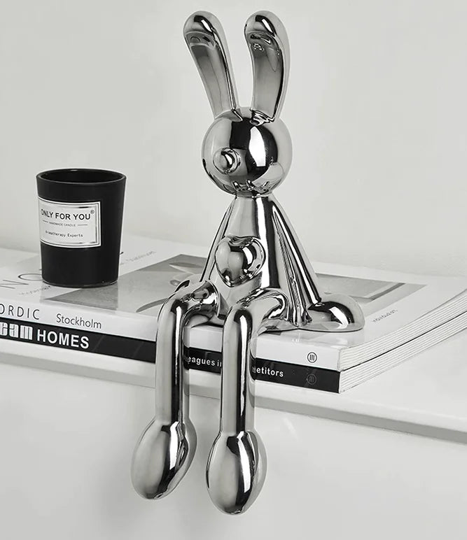 Electroplated metallic rabbit figurine with shiny finish for modern home decor on a magazine with a candle in the background
