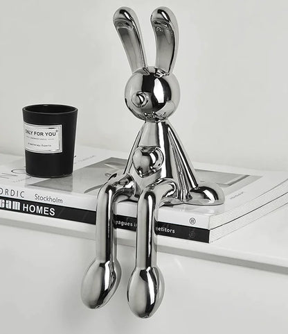 Electroplated metallic rabbit figurine with shiny finish for modern home decor on a magazine with a candle in the background