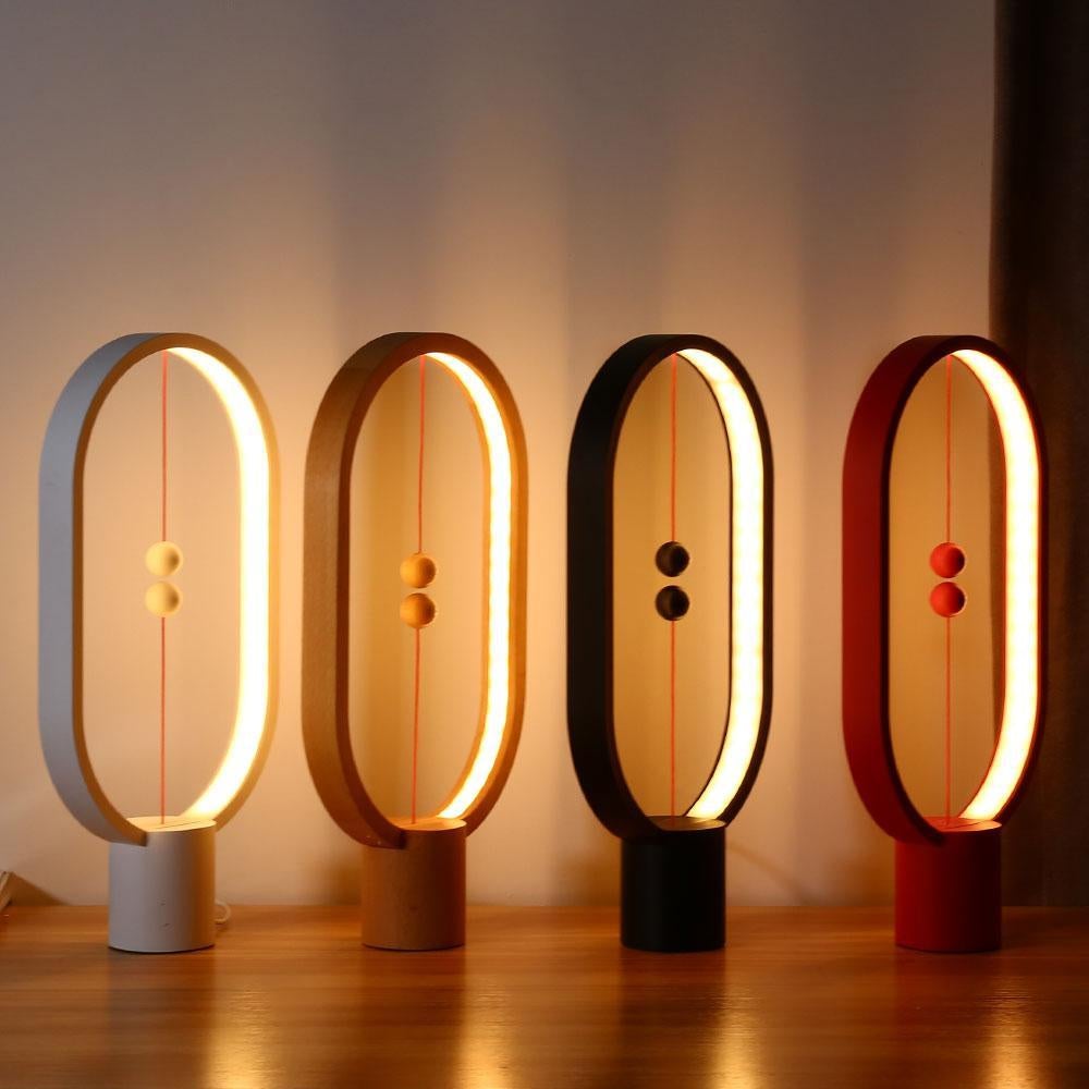 Four LED magnetic table lamps with suspended magnetic sphere switch creating ambient warm lighting with different colours on a wooden surface.