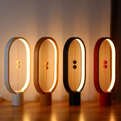 Four LED magnetic table lamps with suspended magnetic sphere switch creating ambient warm lighting with different colours on a wooden surface.