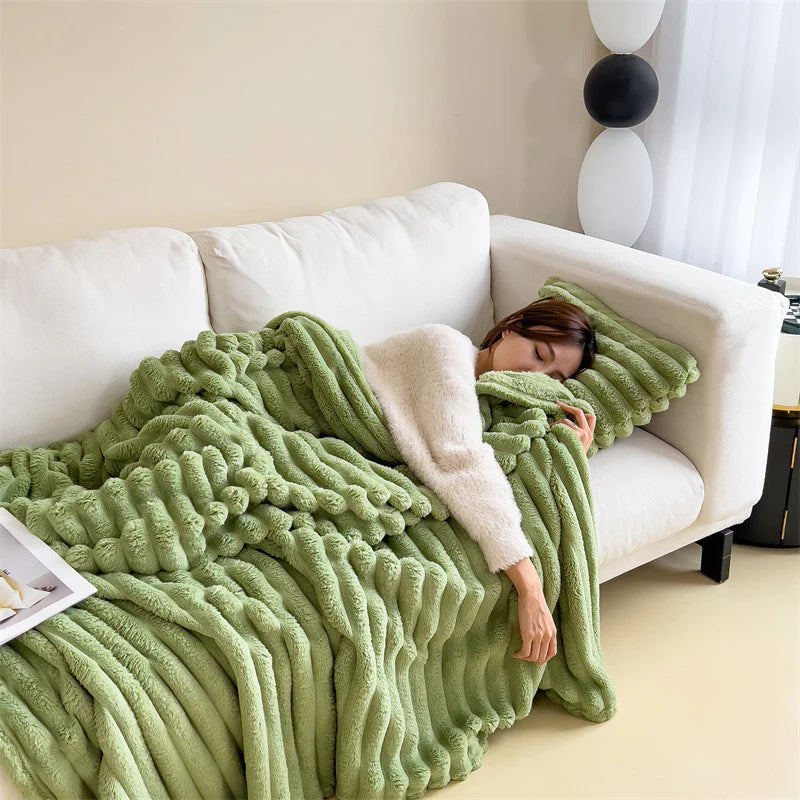 Green cosy ribbed fleece throw blanket in neutral colour draped over couch, soft textured warm blanket for home comfort and relaxation.