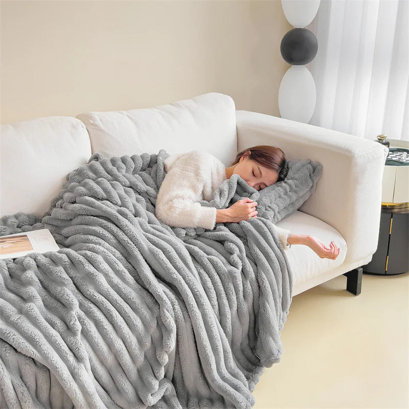 Light Grey cosy ribbed fleece throw blanket in neutral colour draped over couch, soft textured warm blanket for home comfort and relaxation.
