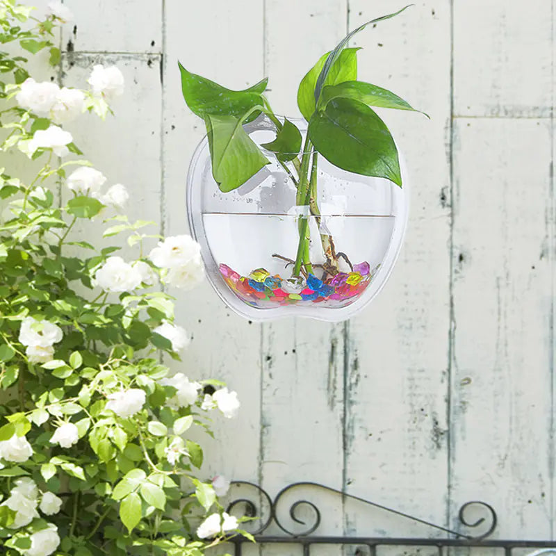 Modern wall planter 21x23cm in contemporary design with plant and goldfish against a stone wall background with a plant and colourful pebbles against a white wooden background.