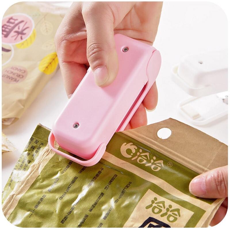 Pink Mini heat bag sealer device creating airtight seal on a green package with visible brand name.