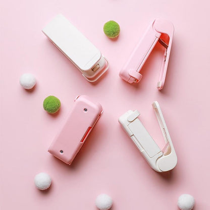 Pink and white Mini heat bag sealer devices on a pink background with decorative items.