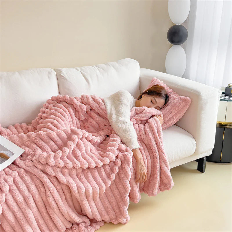 Pink cosy ribbed fleece throw blanket in neutral colour draped over couch, soft textured warm blanket for home comfort and relaxation.