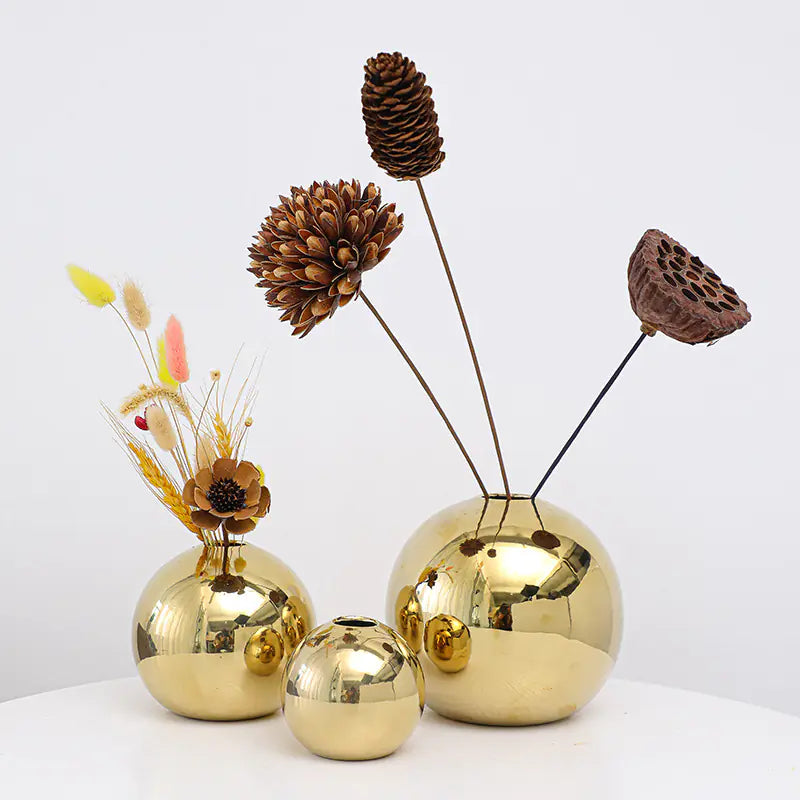 Set of luxurious gold decorative vases with natural elements on a white background