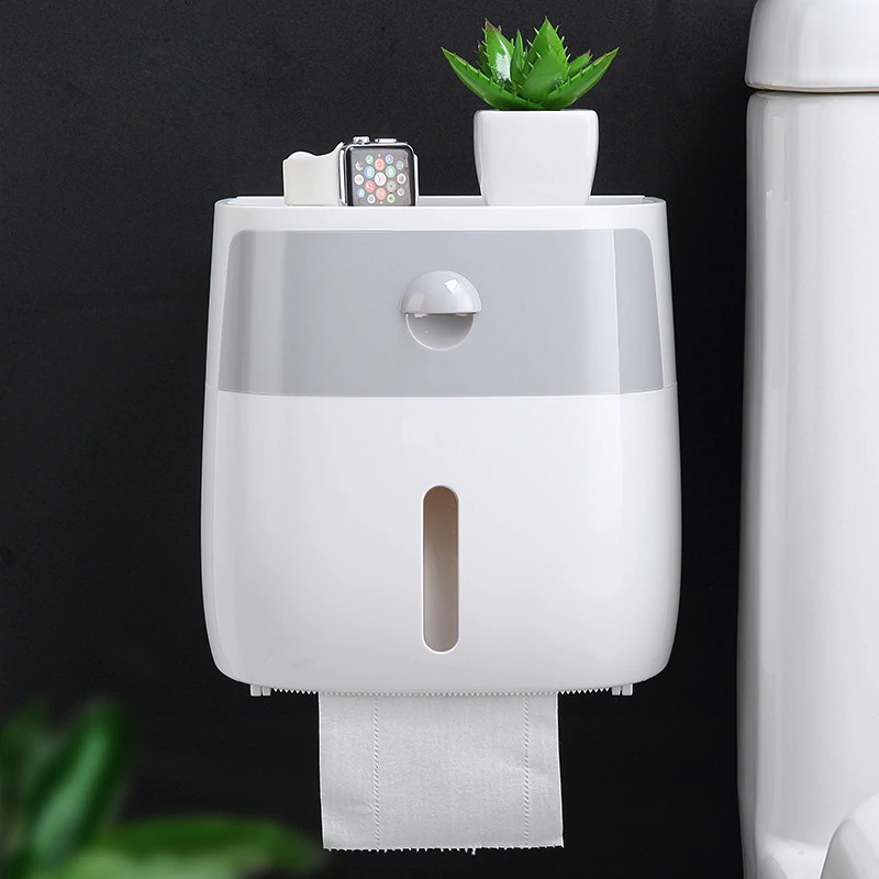 White & Grey wall mounted waterproof toilet paper holder with storage drawer with a plant and smartwatch on top against a black background.