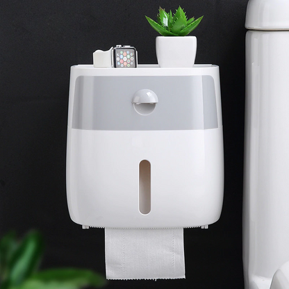 White & Grey wall mounted waterproof toilet paper holder with storage drawer with a plant and smartwatch on top against a black background.