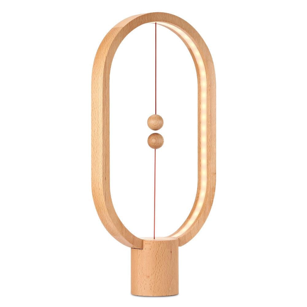 Wood Modern LED magnetic table lamp with suspended magnetic sphere switch creating ambient warm lighting on a white background