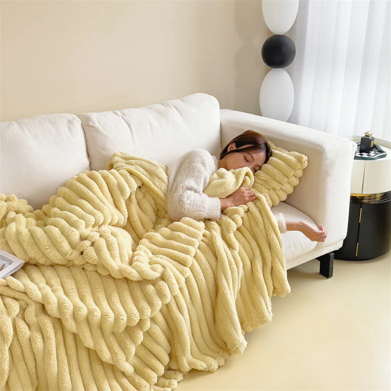 Yellow cosy ribbed fleece throw blanket in neutral colour draped over couch, soft textured warm blanket for home comfort and relaxation.